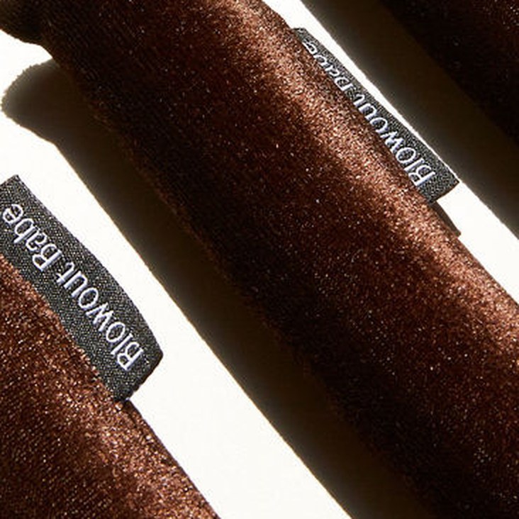 Close-up of brown velvet blowout rods showing the textured grip side and the Blowout Babe label